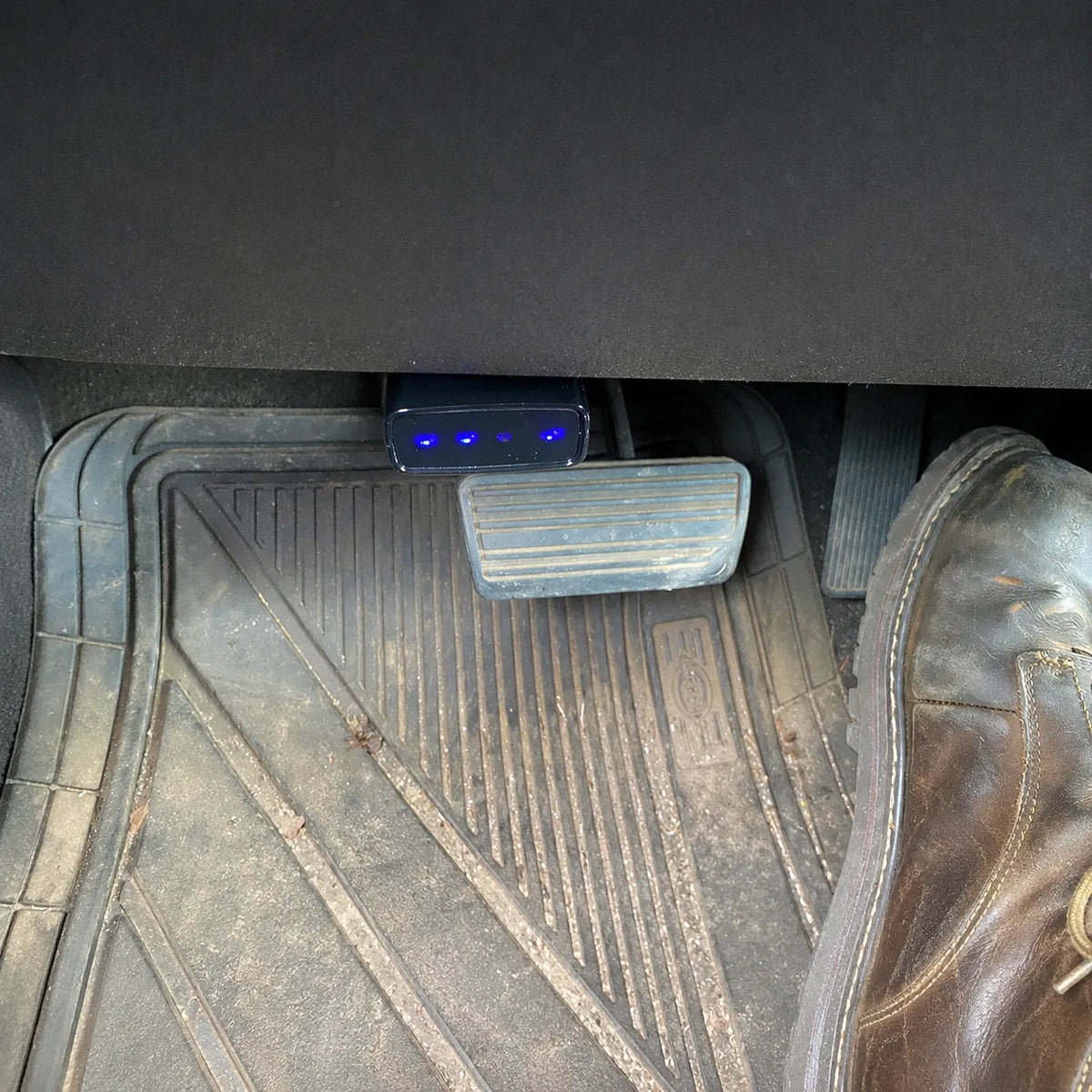 MOQWAIG AFM DFM disabler plugged into the OBD-II port under the dashboard with blue indicator lights active.